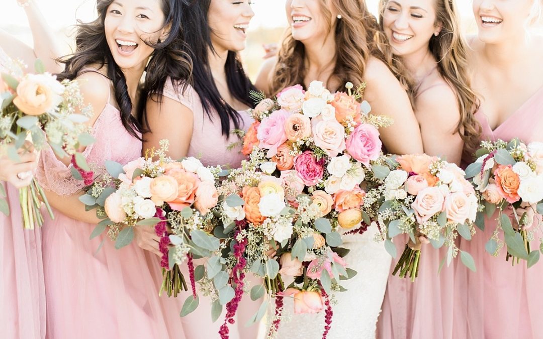 Bridal party holding flowers and smiling at outdoor event space