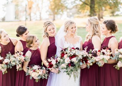bridal party smiling at outdoor wedding venue photoshoot