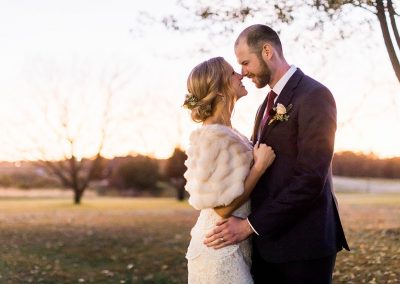 bride and groom in front of beautiful outdoor wedding venue sunset