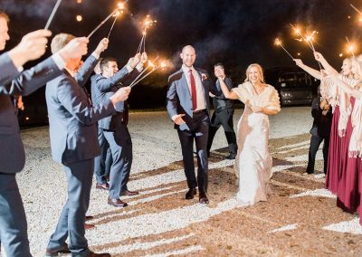 newlyweds walking through sparklers at outdoor wedding venue