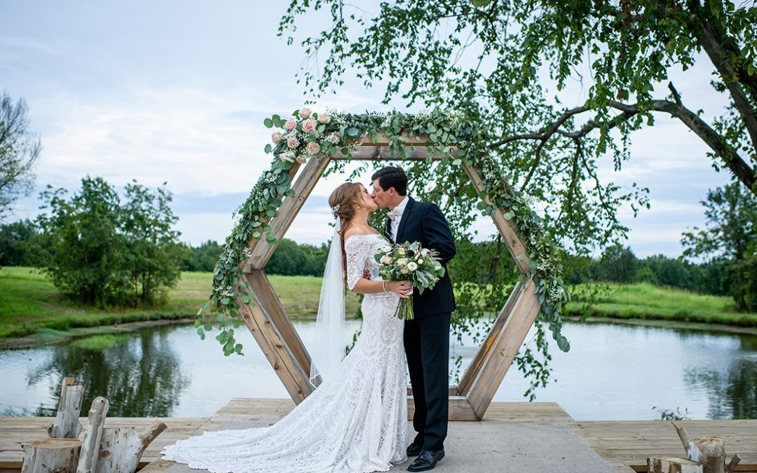 couple standing in front of flower covered arch on wedding day